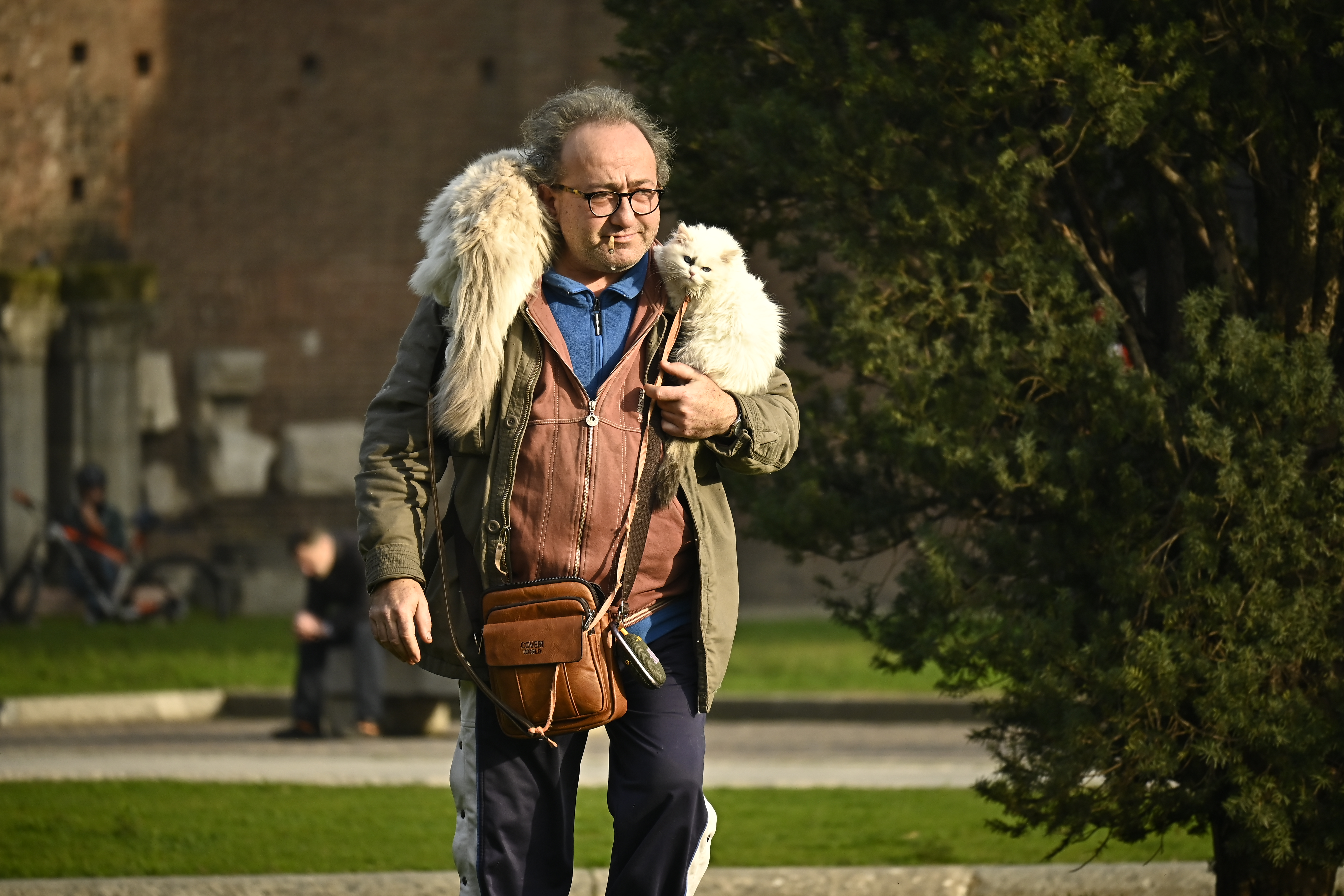 Man in a red hoodie carrying two cats on his shoulders